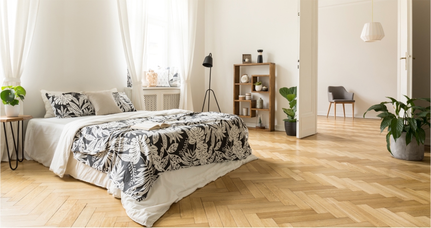 A white bedroom with wooden floors and a black and white bed.