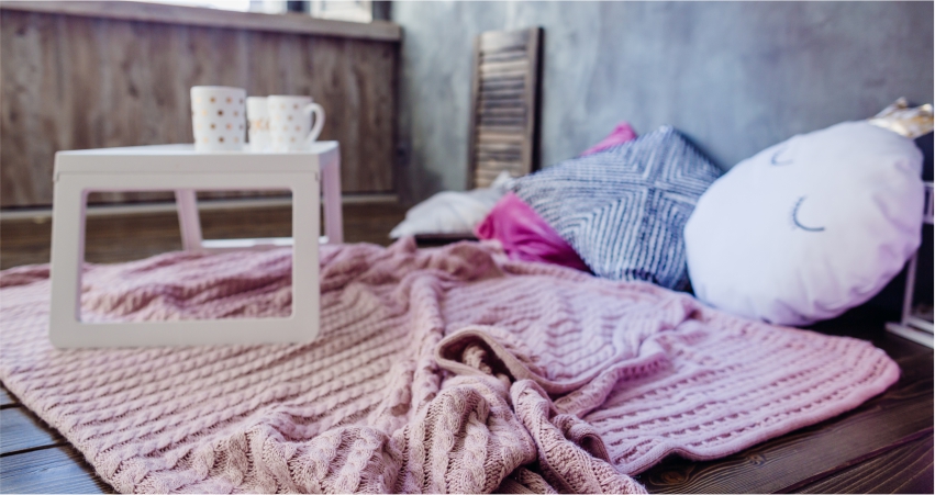 A pink blanket on a wooden floor.