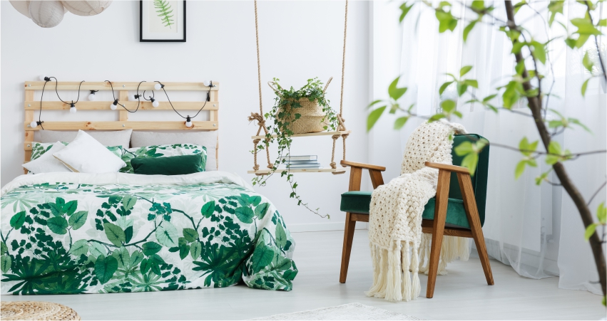 A green and white bedroom with plants and a bed.
