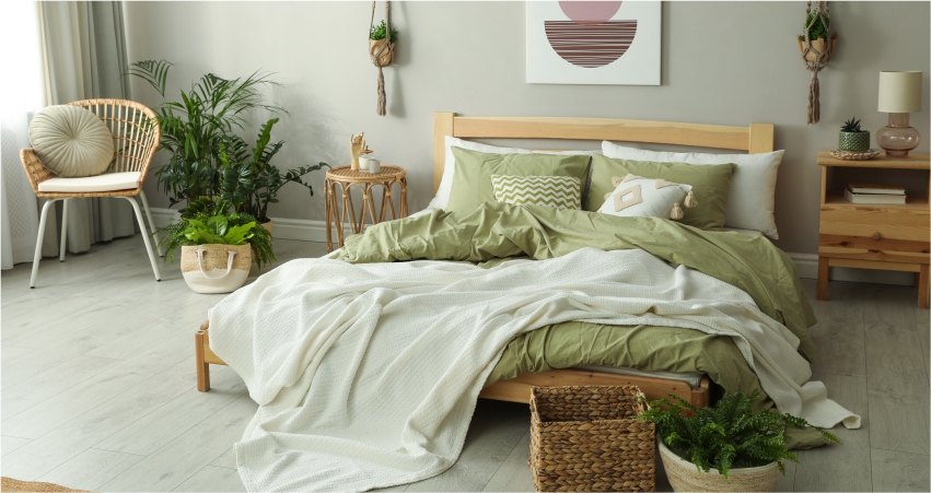 A bedroom with green bedding and a plant on the bed.