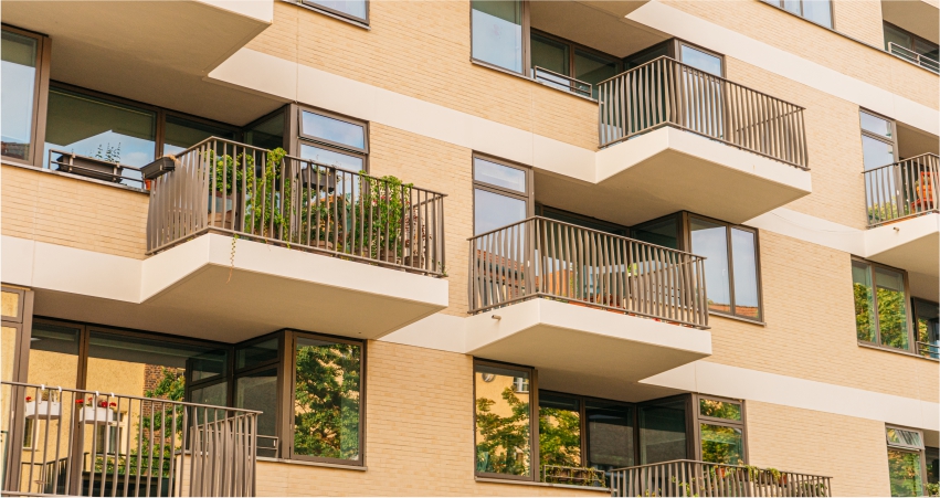 An apartment building with balconies and plants.