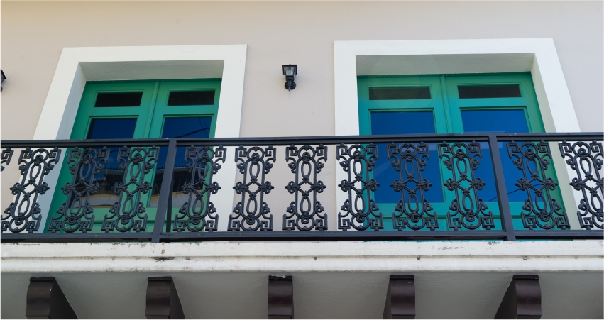 A balcony with green shutters and wrought iron railings.