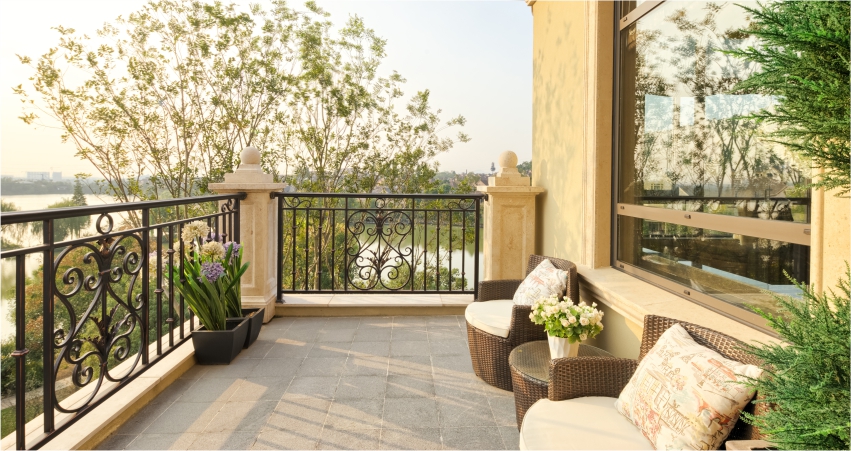 A balcony with wrought iron railing and wicker furniture.
