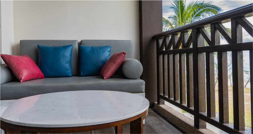 A couch and table on a balcony overlooking the ocean.