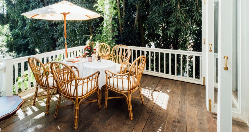 A wicker table and chairs on a wooden deck.