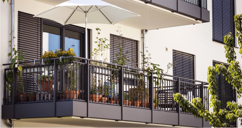 A balcony with potted plants and an umbrella.