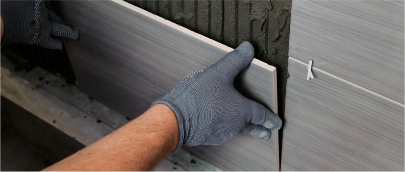 person fixing the wall tile using cement 