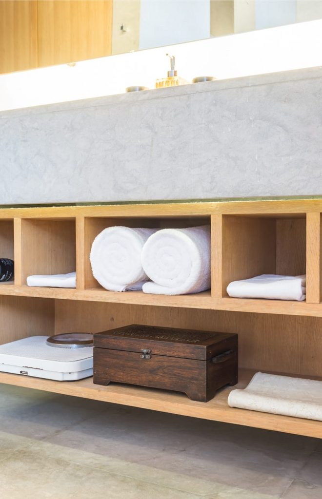 A bathroom with a wooden shelf and towels on it.