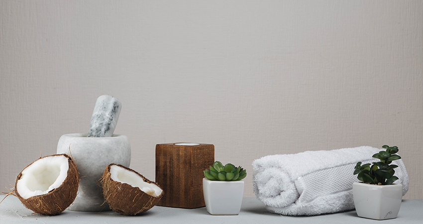 A white towel, a coconut, and a plant on a table.
