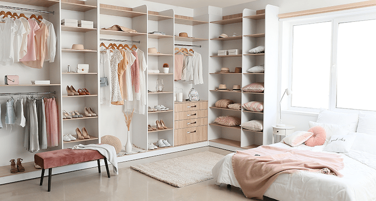 A bedroom with a designer closet full of clothes and shoes.