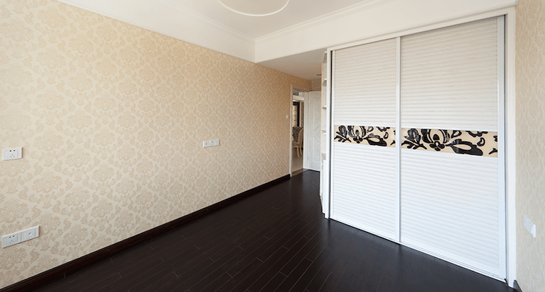 A wooden floor in a room with a floor to ceiling cupboard.