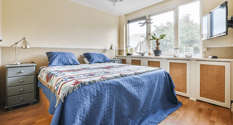 A bedroom with a bed, a tv and window-side narrow cabinet