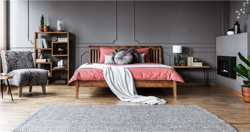 A bedroom with grey walls and a pink bed.