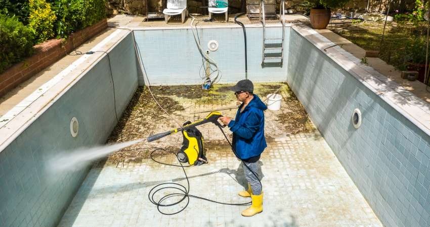 person cleaning swimming pool with jet spray