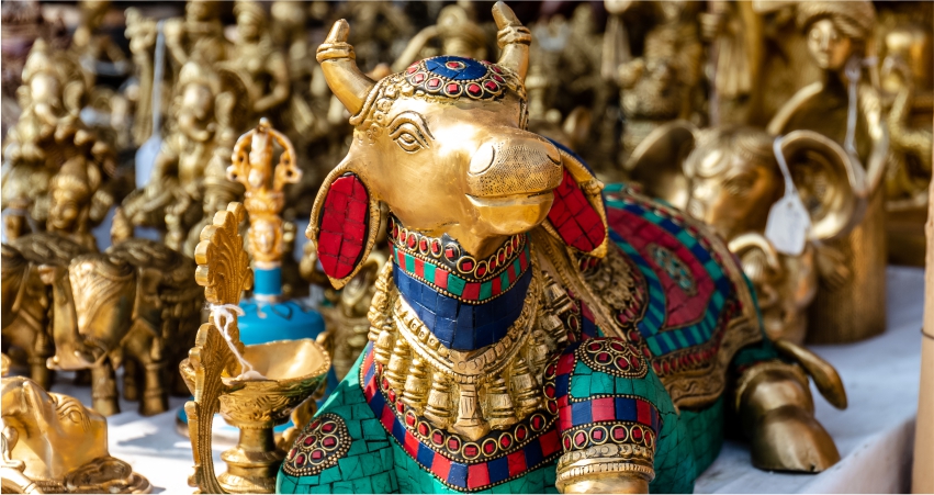 A gold statue of a cow sitting on a table.
