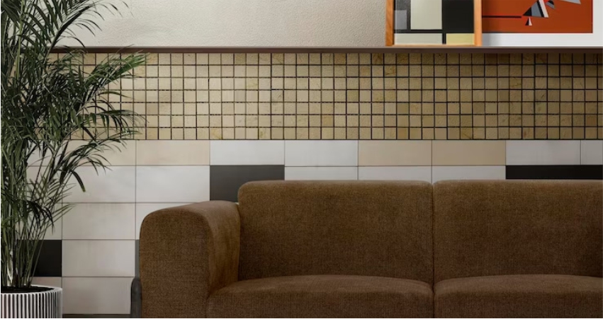 A brown couch is in front of a tiled wall.