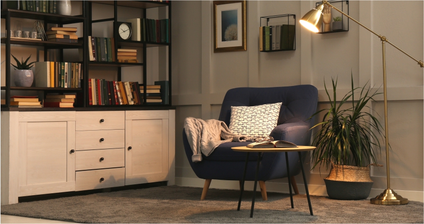A living room with bookshelves, a blue chair and a vertical shelves and storage.