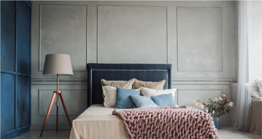 A bed in a bedroom with must-have moulded texture wall and a bedside lamp. 