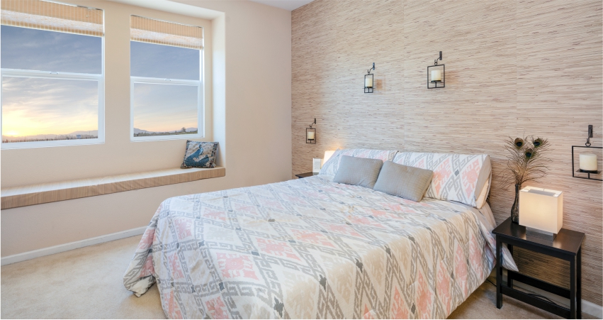 A bedroom with a bed, a glorious grasscloth wallpapers texture design wall and a window overlooking the sunset.