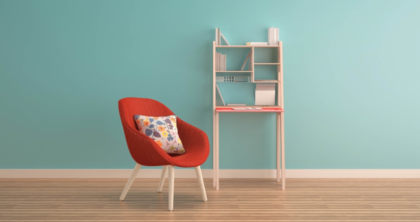 A chair and a bookcase in front of a blue wall.