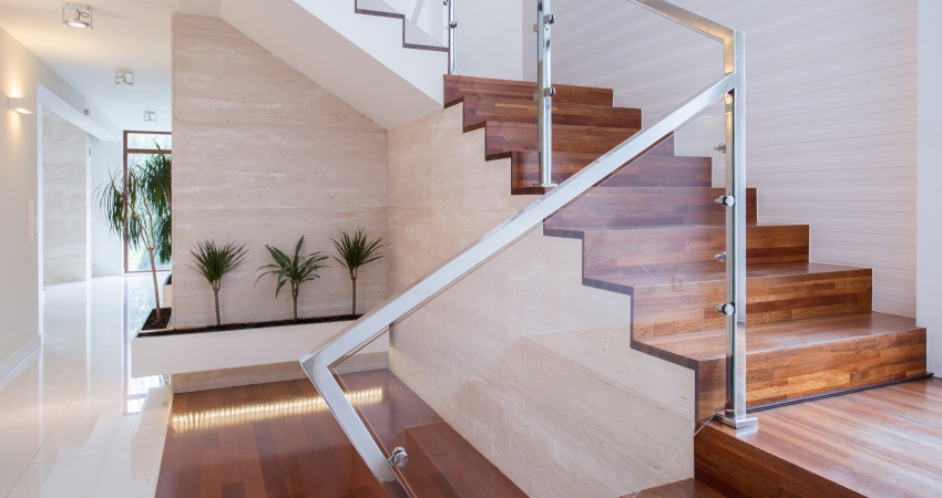 A wooden staircase in a modern home with glass railings.