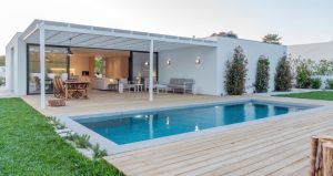 A modern single floor house with a swimming pool and wooden deck.
