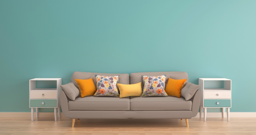 A gray couch in front of a turquoise wall.