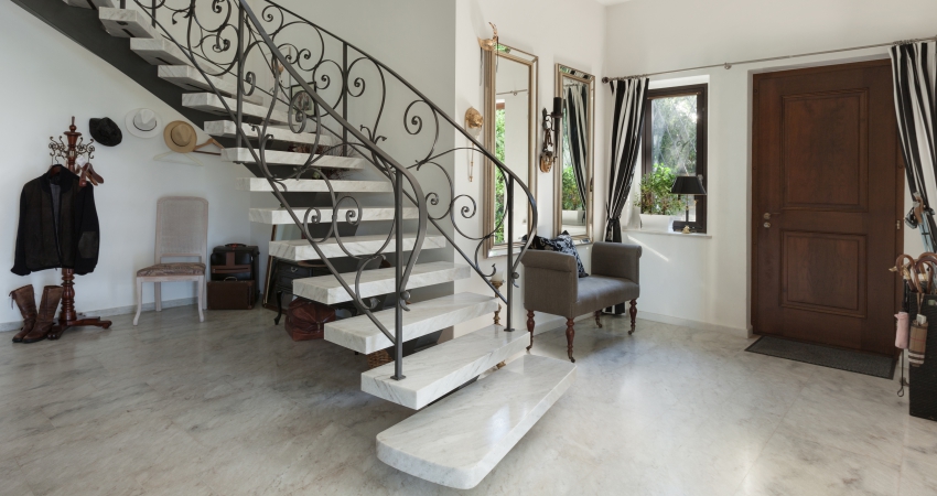 A marble staircase in a house with wrought iron railings.