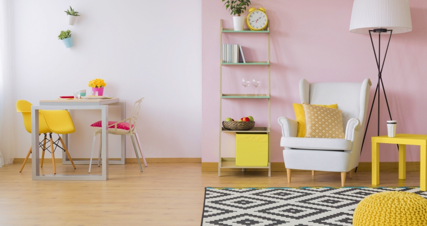 A living room with pink walls and yellow furniture.