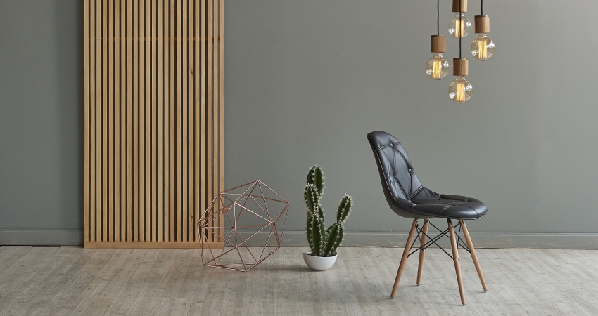 A black chair with a cactus in front of a wooden and grey wall.