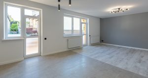 An empty room with grey walls and wooden floors.