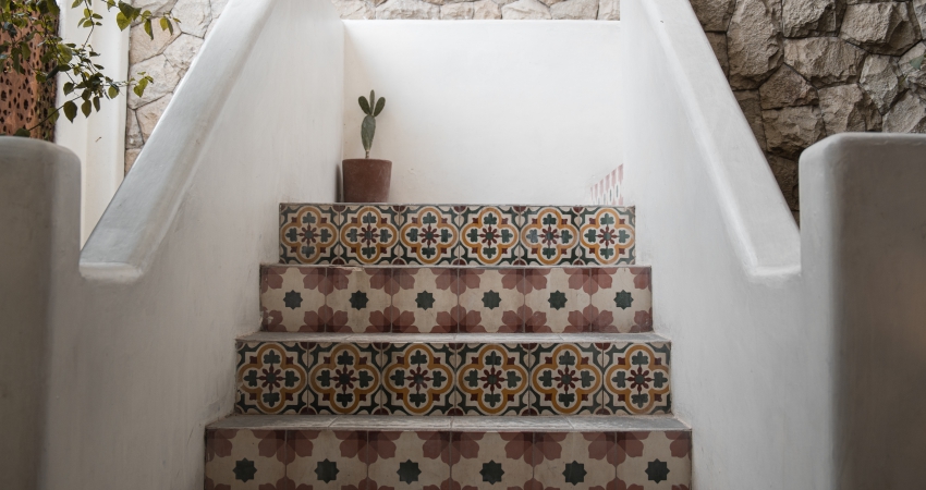 A staircase with mexican tiled steps and a potted plant.