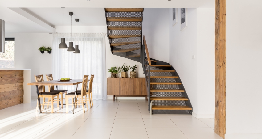 A modern kitchen with wooden floors and a half landing staircase.
