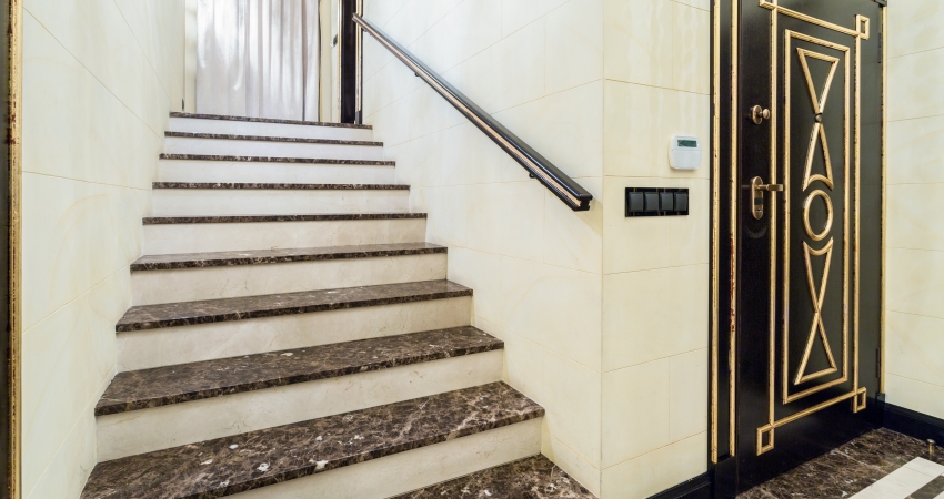 A black granite stairway with a gold door and a marble floor.