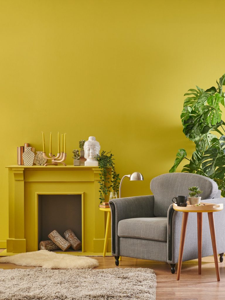A living room with mustard yellow walls and a grey couch.