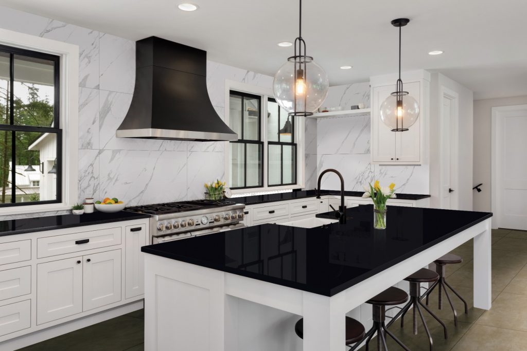 A white kitchen with black marble counter tops.