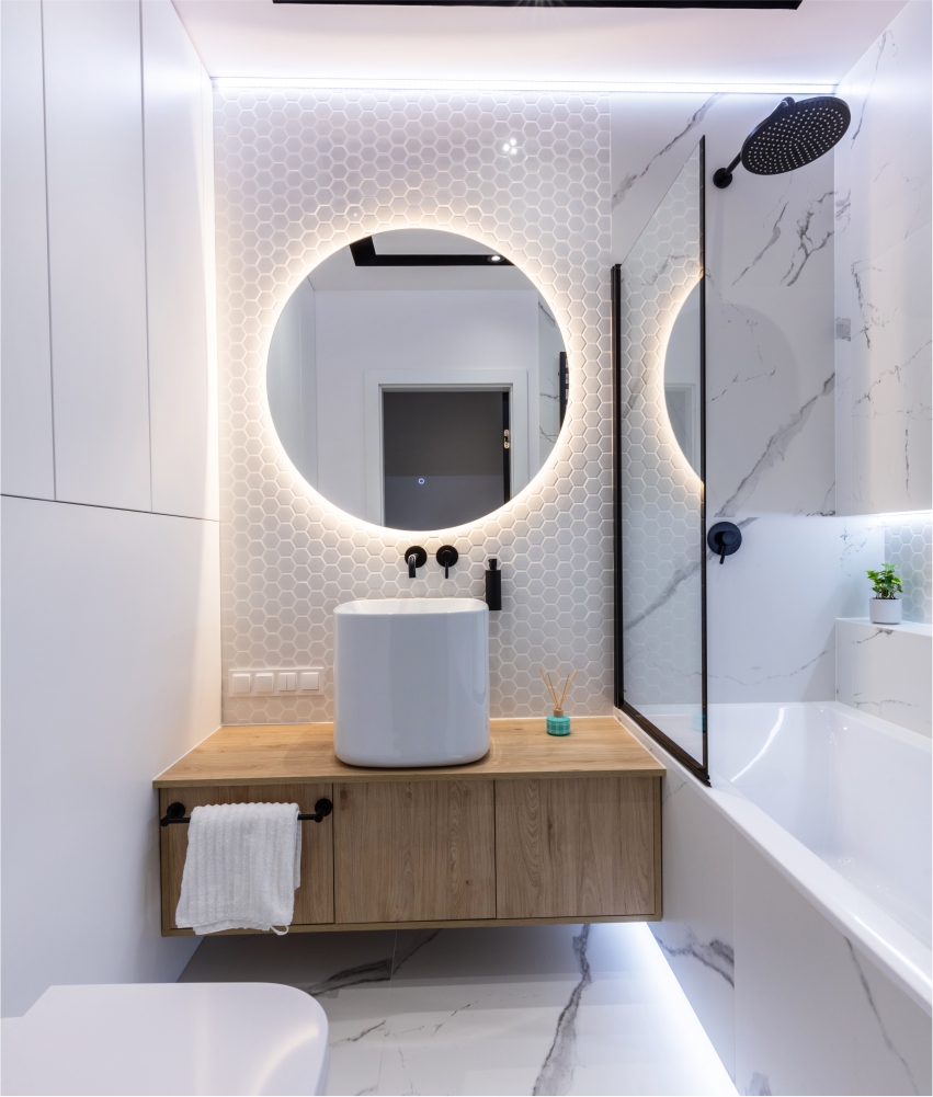 A modern bathroom with white walls and a round mirror.