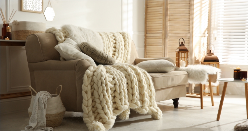 A living room with a white couch and a beige throw blanket.