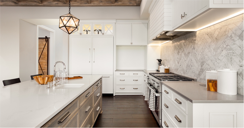 A white kitchen with a marble counter top.