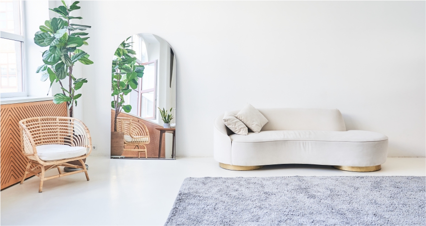 A white living room with a wicker chair and a plant.