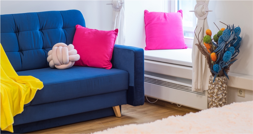 A blue couch with pink pillows in living room corner.