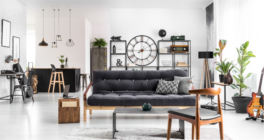 A white living room with a black couch and a clock.