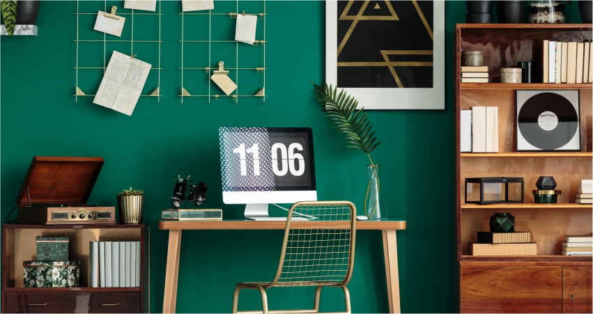 A room with green walls and a desk and bookshelf.