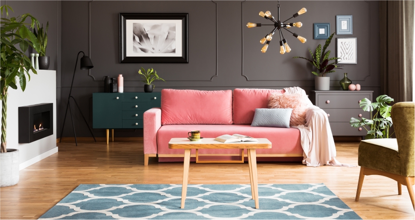 A living room with a pink couch and a green rug.