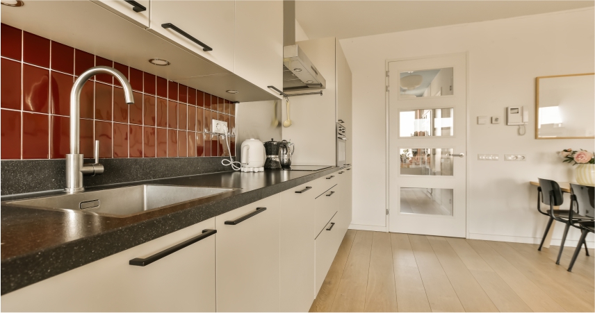 A kitchen with red and white tiled walls and a sink.