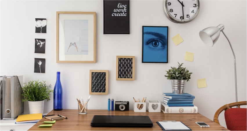 A study desk with various items on it and a clock on the wall.