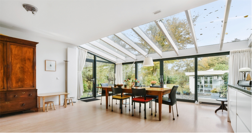 A kitchen with large windows, ceiling and a dining table.