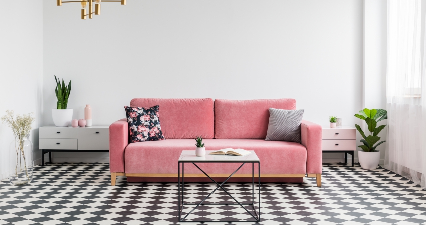 A pink sofa in a room with black & white checkered floor tiles.