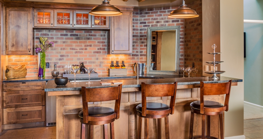 A kitchen with a brick wall and bar stools.