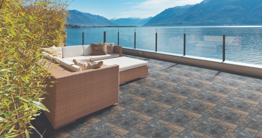 A patio with wicker furniture, slate tiles and a view of the lake.